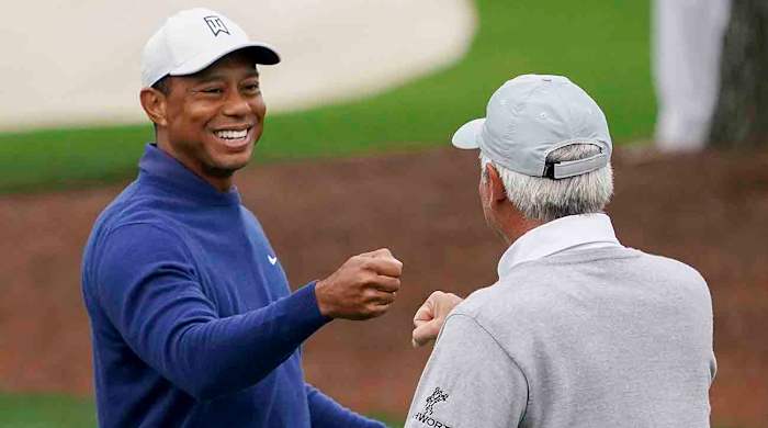 Tiger Woods gives Fred Couples a fist bump during a 2023 Masters practice round.